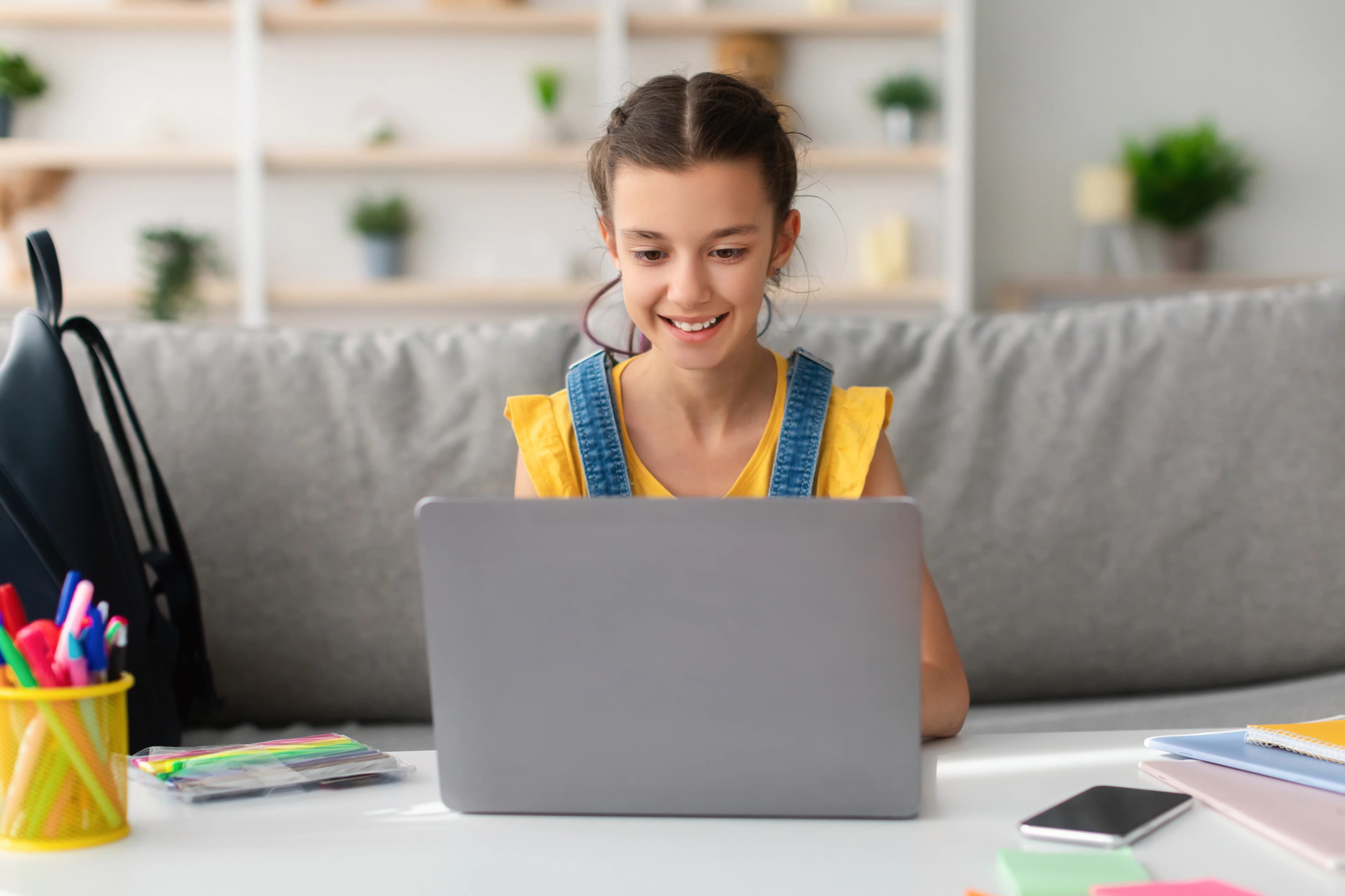 A homeschool student smiling while working on her laptop